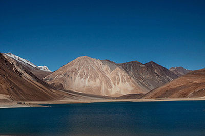 Scenic view of lake and mountains against clear blue sky