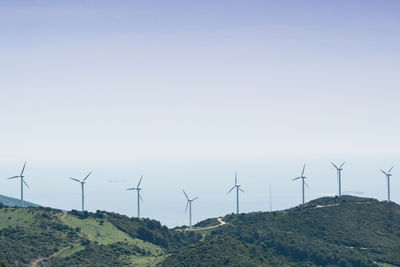 Wind turbines on field against sky