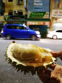 Close-up of hand holding ice cream cone on road in city