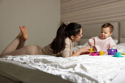 Mother and daughter sitting on bed at home