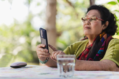 Senior woman using smart phone outdoors in the garden.