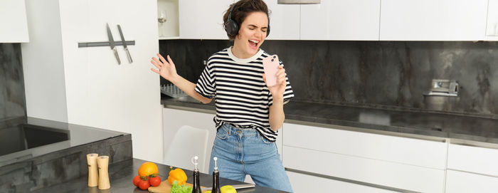 Full length of young woman standing against wall