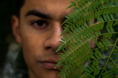 Close-up portrait of young man by plant