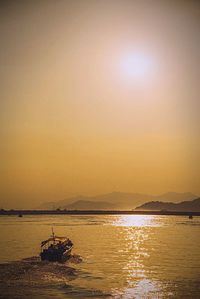 Boats in calm sea at sunset