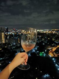 Man holding glass of cityscape against sky