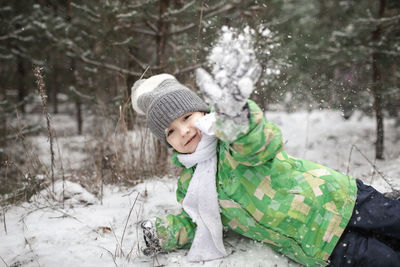 Boy playing on snow during winter