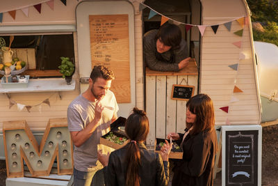 High angle view of male food truck owner looking at customers on street