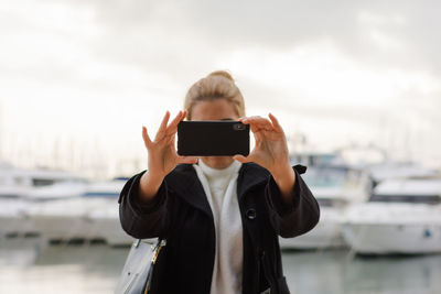 Young woman takes a photo with her smartphone looking at camera