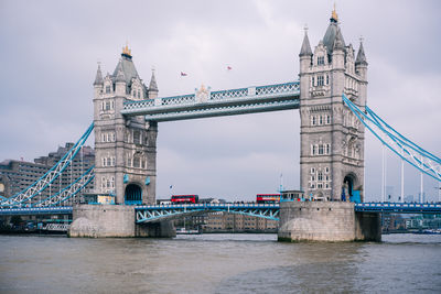 Low angle view of bridge over river against cloudy sky