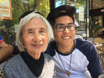 Portrait of teenage boy with grandmother at outdoors cafe