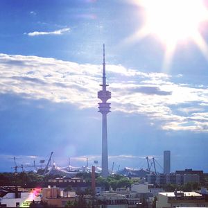 Communications tower in city against sky