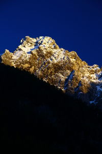 Low angle view of rocks against clear blue sky