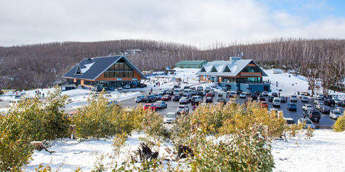 Houses on snow covered field by buildings against sky