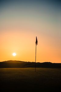 Silhouette street light on field against sky during sunset