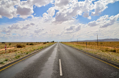 Country road against cloudy sky