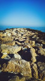 Aerial view of rocks on beach against clear blue sky