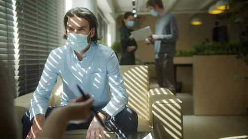 Man wearing mask having discussion at office