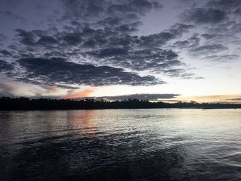 Scenic view of lake against dramatic sky during sunset