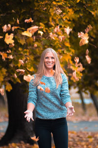 Portrait of smiling young woman standing during autumn