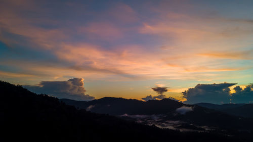 Scenic view of silhouette mountains against dramatic sky