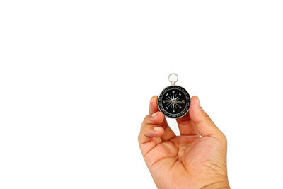 Close-up of hand holding clock against white background