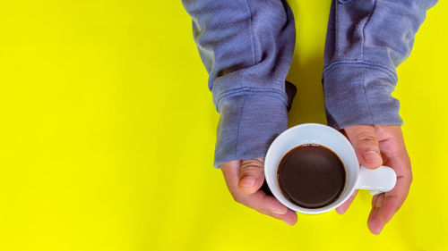 Directly above shot of hand holding coffee cup