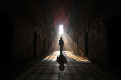 Rear view of silhouette man standing in dark corridor