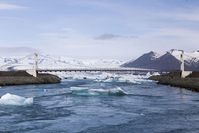 Cable-stayed glacial river bridge at jokulsarlon, with tourists roaming the area