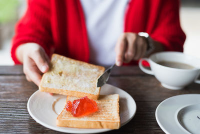 Midsection of woman applying jam on bread