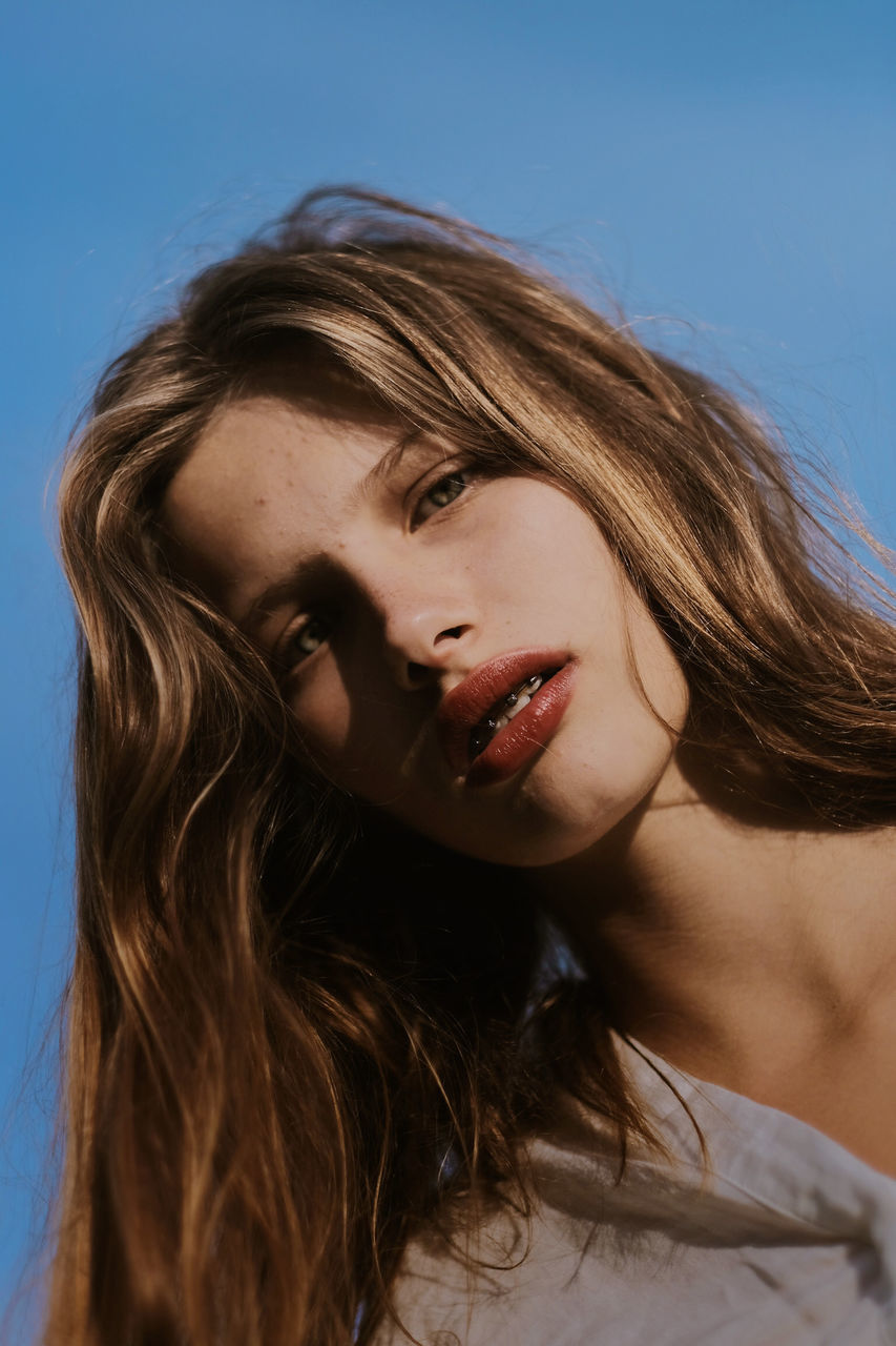 portrait, hair, hairstyle, long hair, headshot, one person, brown hair, young adult, women, blue, beauty, young women, close-up, looking at camera, beautiful woman, studio shot, adult, front view, blue background, teenager, contemplation, human hair