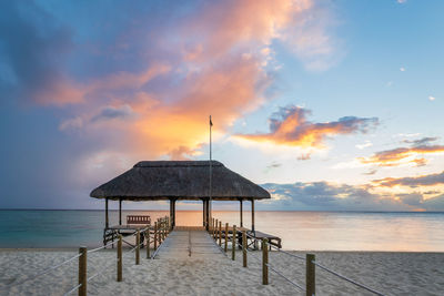 Lifeguard hut on beach against sky during sunset