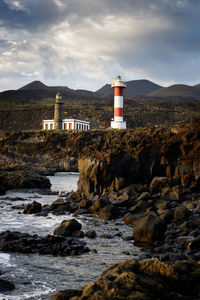 Lighthouse on rocks against sky