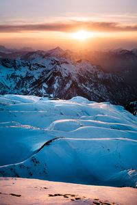 Scenic view of snow covered land against sky at sunset