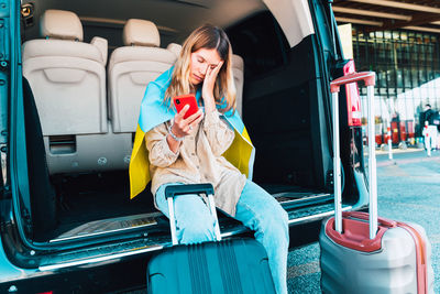 Young woman using phone while sitting in car