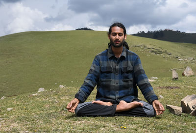 A indian young man practicing yoga in lotus pose, padmasana with gyan mudra in the mountain.