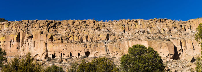 Primitive dwellings in rock against blue sky