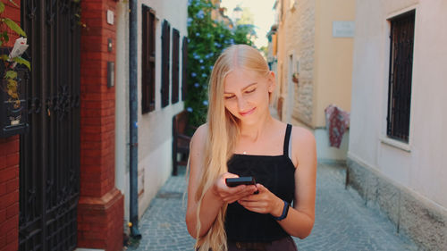 Young woman using mobile phone while standing on building