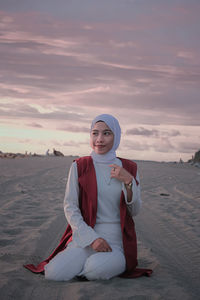 Portrait of smiling young woman on beach against sky during sunset