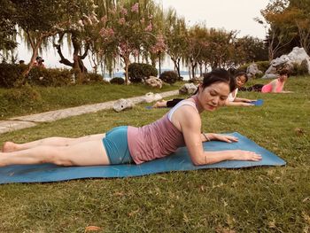 Full length of woman exercising while lying on mat over grass