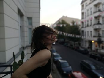 Side view of young woman standing in city