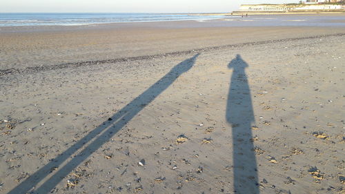 Shadow of people on beach against sky