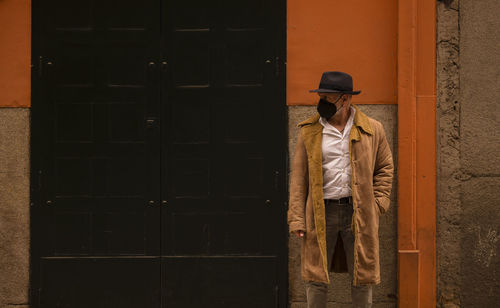 Portrait of adult man in hat and mask against wall on street. madrid, spain