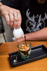 Close-up of hand pouring coffee in cup on table