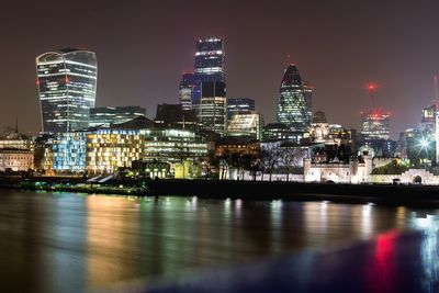 Thames river by illuminated cityscape at night