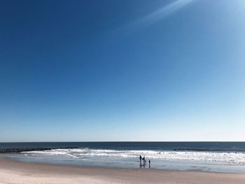 Scenic view of beach against clear blue sky