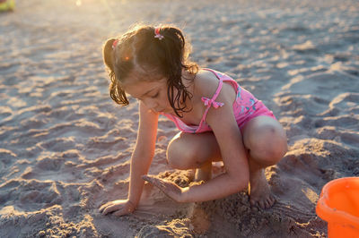 Young girl is playing with beach toys in the sand