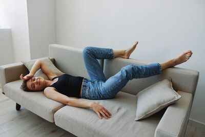 Low section of woman sitting on sofa at home