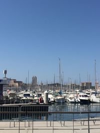 Sailboats moored at harbor against clear blue sky