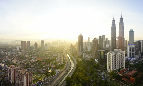 Petronas towers and cityscape against sky during sunrise