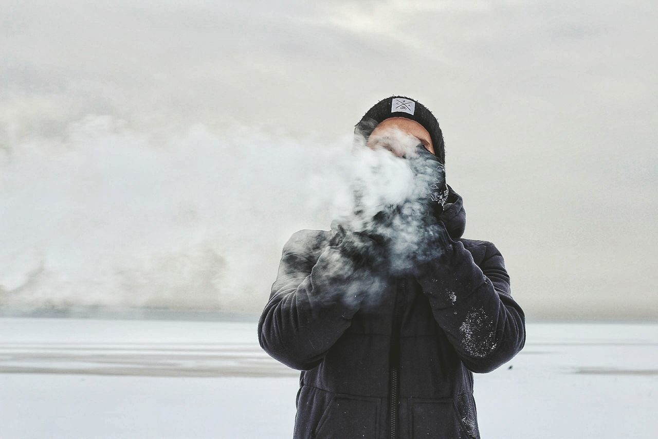 MAN STANDING ON BEACH AGAINST SKY